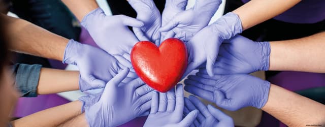 viele im Kreis angeordnete, blau behandschuhte Hände halten rotes Herz