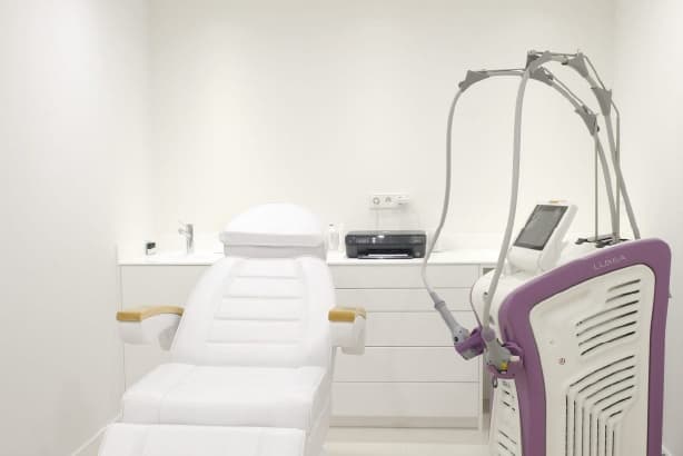 sillón blanco con una máquina de tratamientos dermatológicos de color blanco y morado