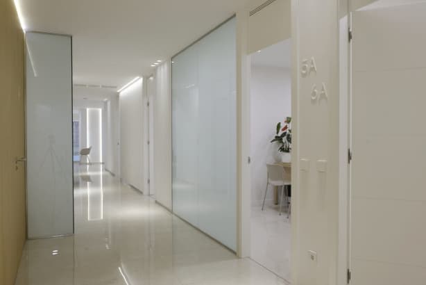 pasillo blanco con puerta abierta y número de la sala en la pared