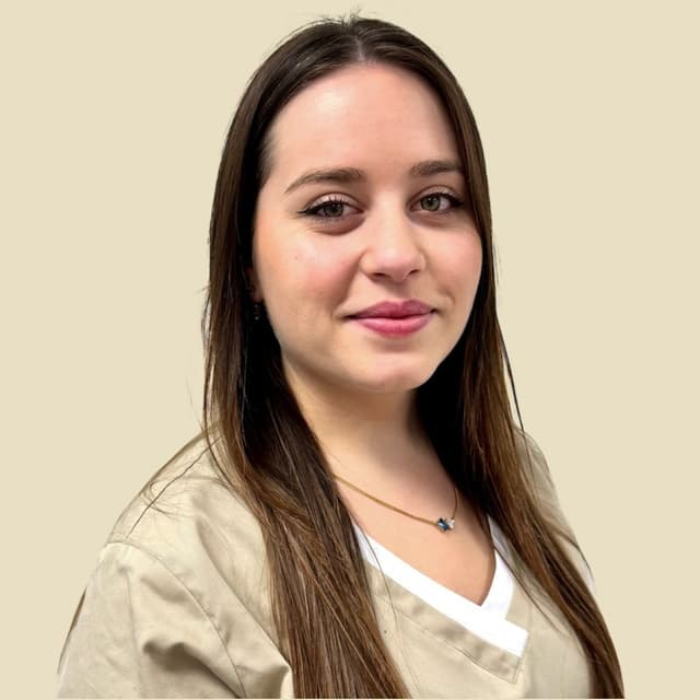 Frau in beigefarbener Kasack, lächelnd, in einem runden Rahmen vor neutralem Hintergrund.