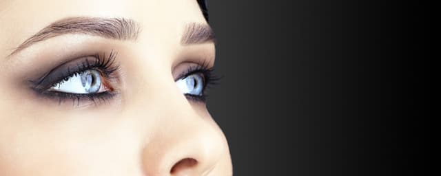 Mulher sobre fundo cinzento escuro e mão no rosto