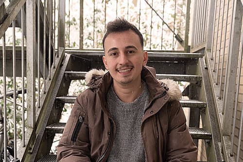 Albian Berisha sitzt auf Treppe.